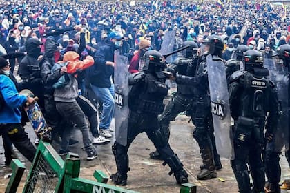 Manifestantes chocan con la policía antidisturbios durante una protesta contra un proyecto de reforma tributaria lanzado por el presidente colombiano Iván Duque, en Bogotá, Colombia