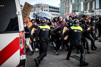 Manifestantes chocan contra policías antidisturbios holandeses durante una protesta contra las restricciones del coronavirus en la plaza de Eindhoven, Países Bajos, el 24 de enero de 2021