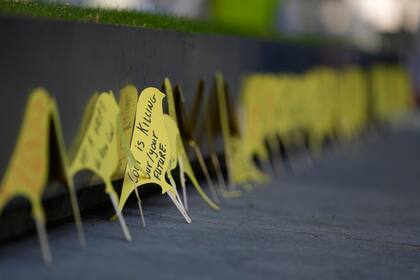 Manifestantes colocan carteles amarillos con forma de canario frente a la secretaría de Interior británica durante una manifestación contra la propuesta de abrir una mina de carbón de coque en el norte de Inglaterra, en Londres, martes 7 de setiembre de 2021.  (AP Foto/Alastair Grant)