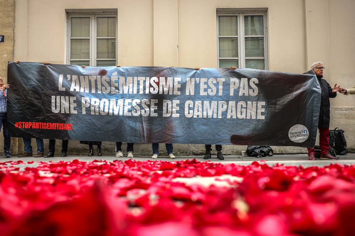 Manifestantes contra la extrema izquierda muestran una pancarta que dice, "El antisemitismo no es una promesa de campaña", cerca de la entrada donde se realizará la conferencia de prensa de los líderes de los partidos izquierdistas franceses para la próxima elección