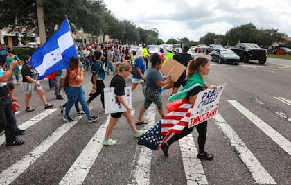 Manifestantes cruzan una calle, el jueves 1 de junio de 2023, en Orlando, Florida, durante una protesta contra la nueva ley de inmigración de Florida que promulgó el gobernador Ron DeSantis (Joe Burbank/Orlando Sentinel via AP)