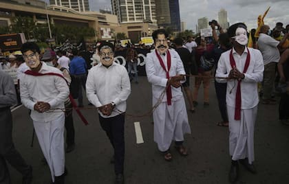 Manifestantes de Sri Lanka llevan máscaras de los miembros de la familia del presidente Gotabaya Rajapaksa durante una marcha que exige la dimisión de Gotabaya, en el lugar de la protesta en curso en Colombo, Sri Lanka, 29 de abril de 2022.