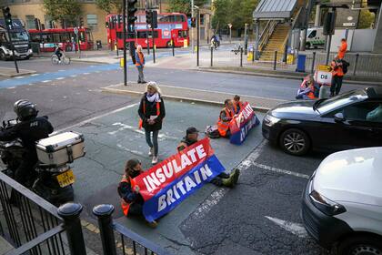 Manifestantes del grupo Aislan Gran Bretaña bloquean una calle cerca del centro financiero Canary Wharf en el este de Londres, el lunes 25 de octubre de 2021. (Victoria Jones/PA vía AP)