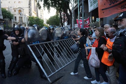 Manifestantes empujan una valla durante enfrentamientos con la policía antidisturbios afuera del Congreso durante las manifestaciones semanales para exigir mejores pensiones para los jubilados y oponerse a las medidas de austeridad del gobierno de Javier Milei, en Buenos Aires, Argentina, el miércoles 26 de marzo de 2025. (AP Foto/Rodrigo Abd)