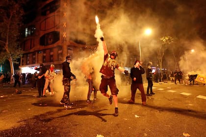 Manifestantes lanzaban de vuelta una granada de gas lacrimógeno a la policía, ayer, en las protestas de Barcelona