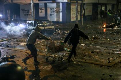 Manifestantes llevan piedras en un carrito de supermercado durante los enfrentamientos con la policía antidisturbios que estallaron durante una protesta contra la muerte de un abogado bajo custodia policial, en Bogotá