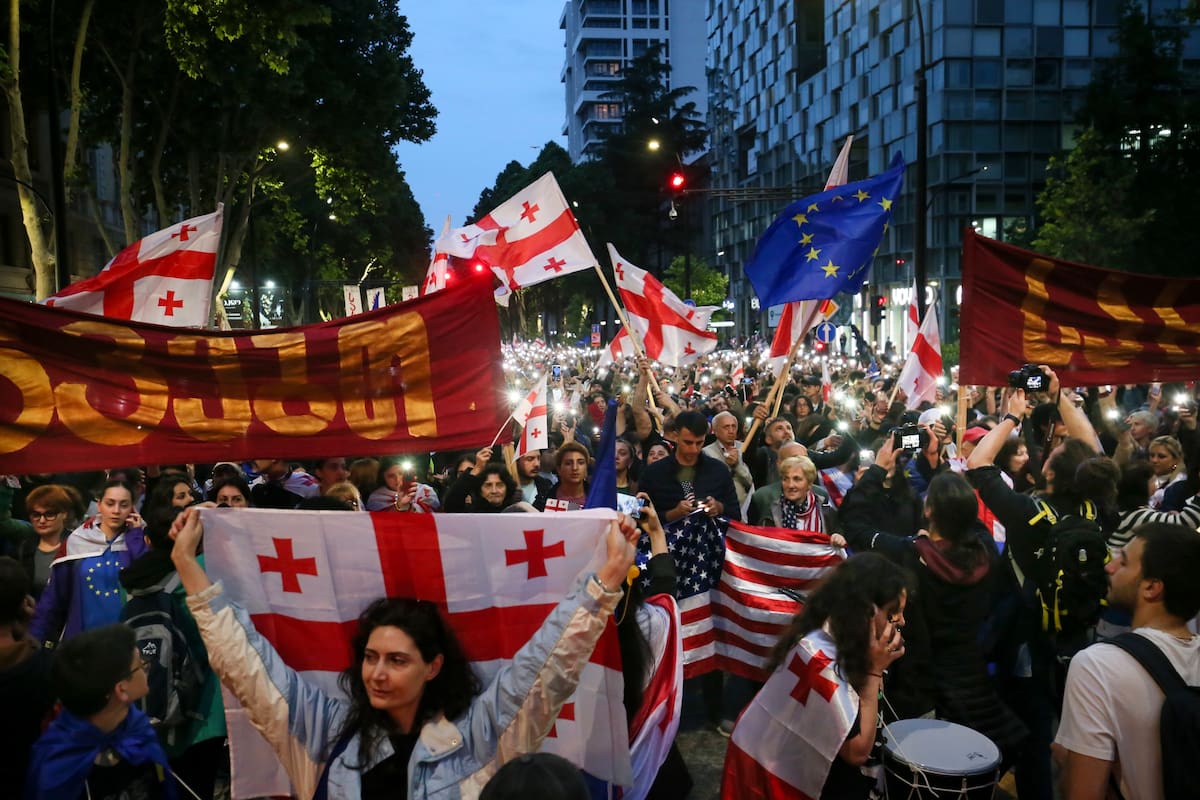Manifestantes ondean banderas de Georgia, Estados Unidos y la Unión Europea durante una marcha de la oposición contra una ley sobre influencia extranjera y para celebrar el Día de la Independencia en Tiflis, Georgia, el domingo 26 de mayo de 2024. La oposición describe la propuesta como "la ley rusa", porque Moscú emplea una legislación similar para perseguir a medios independientes, organizaciones sin fines de lucro y activistas críticos con el Kremlin. (AP Foto/Zurab Tsertsvadze)