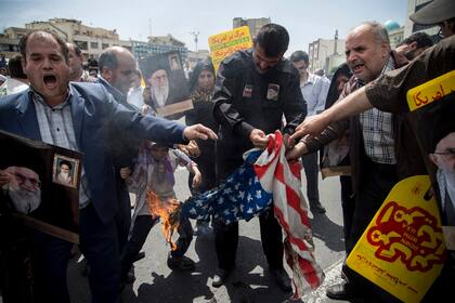 Manifestantes queman una bandera en Teherán