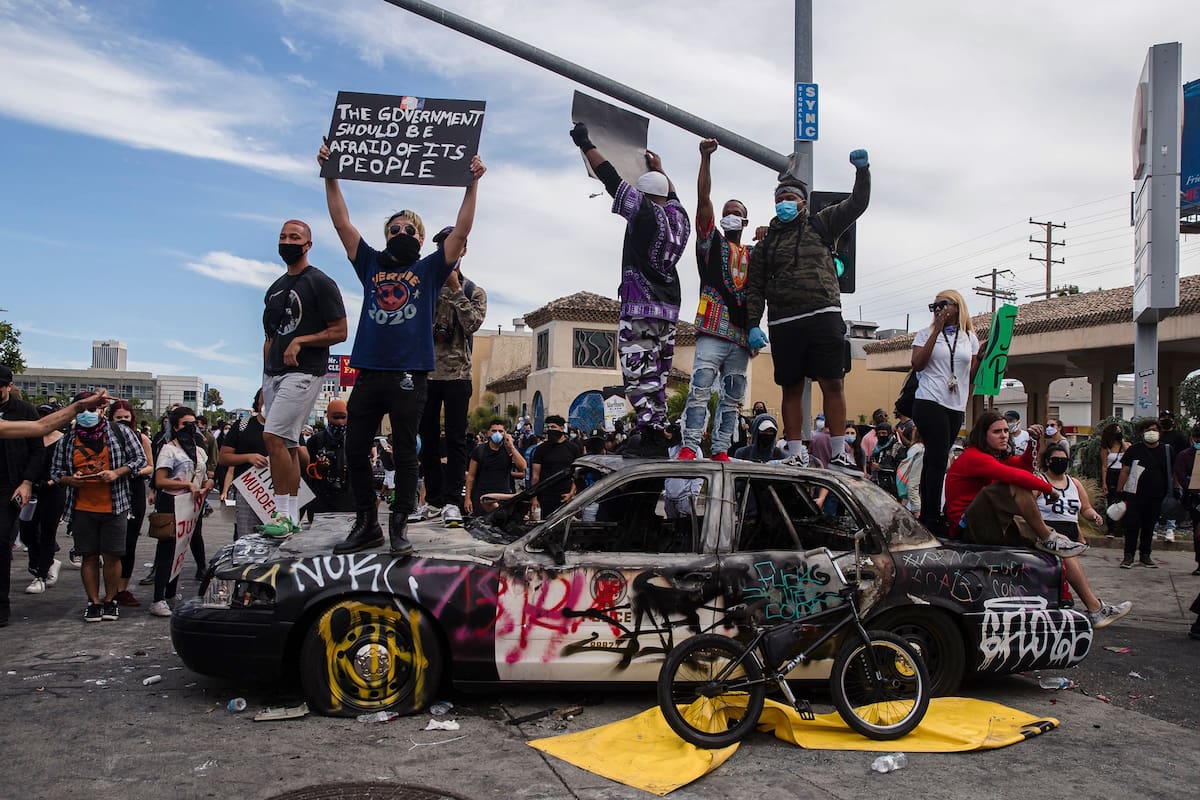 Manifestantes saltan sobre un vehículo policial dañado en Los Ángeles el 30 de mayo de 2020 durante una protesta contra la muerte de George Floyd.