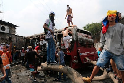 Manifestantes se paran en un autobús incendiado durante los enfrentamientos con la Guardia Nacional Bolivariana en Urena, Venezuela, cerca de la frontera con Colombia.
