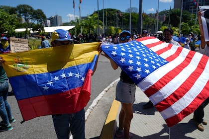 Manifestantes sostienen banderas de Venezuela y Estados Unidos durante una marcha estudiantil que ex