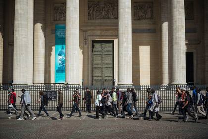 Manifestantes y migrantes pasan por el monumento del Panteón