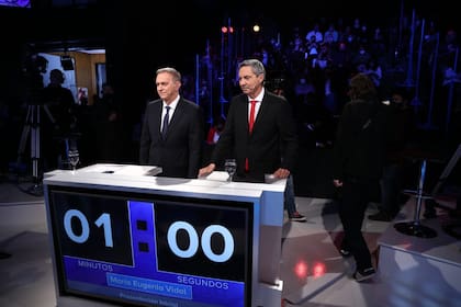 Marcelo Bonelli y Edgardo Alfano, en el estudio donde se realiza el debate. El reloj marca el tiempo disponible para cada candidato.