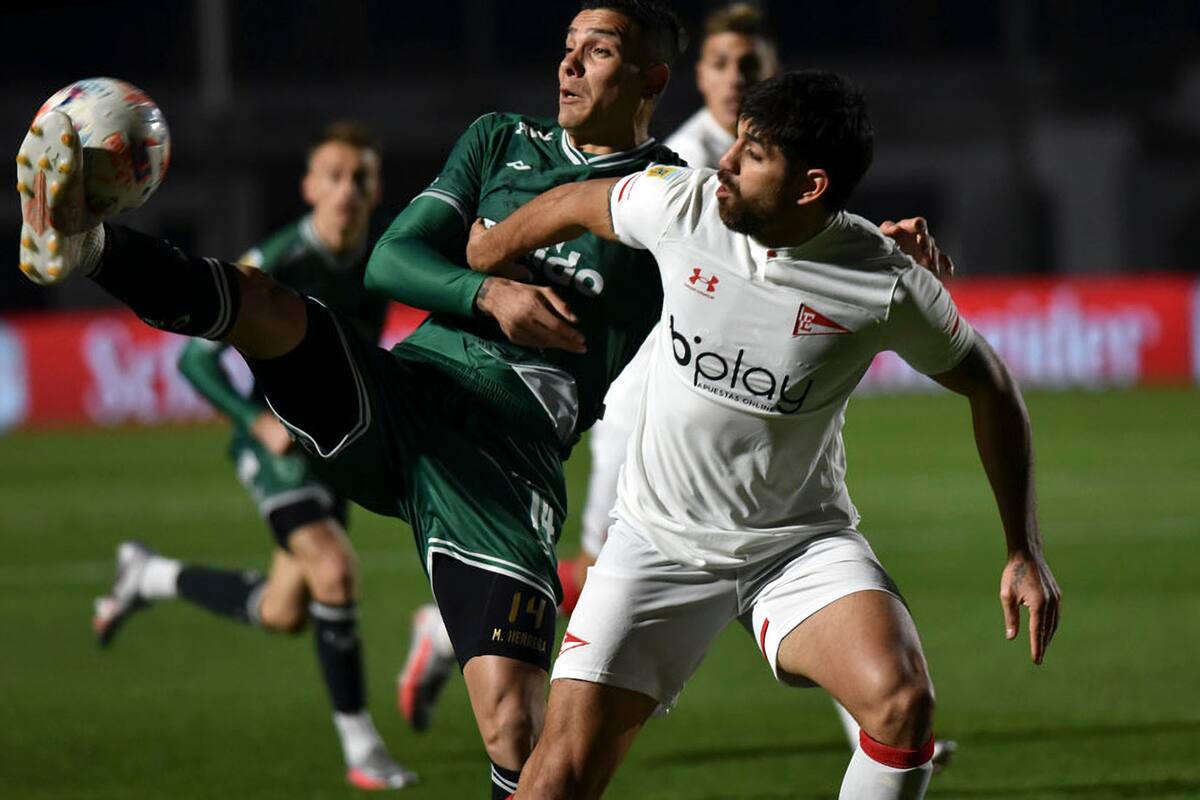 Marcelo Herrera, de Sarmiento, rechaza antes de que la pelota llegue a Leandro Díaz, delantero de un Estudiantes que ganó por 3-0 en Junín y es el primer puntero del Torneo 2021.