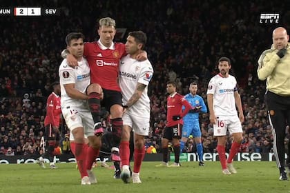 Marcos Acuña y Gonzalo Montiel llevando en andas a Lisandro Martínez, después de su lesión en el partido entre Manchester United y Sevilla
