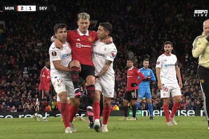 Marcos Acuña y Gonzalo Montiel llevando en andas a Lisandro Martínez, después de su lesión en el partido entre Manchester United y Sevilla
