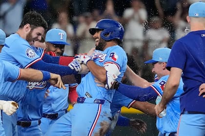 Marcus Semien (centro), de los Rangers de Texas, es felicitado por sus compañeros luego de conectar un sencillo que remolcó al dominicano Leody Taveras en el 9no episodio del juego de béisbol ante los Marineros de Seattle, el domingo 22 de septiembre de 2024, en Arlington, Texas. (AP Foto/LM Otero)