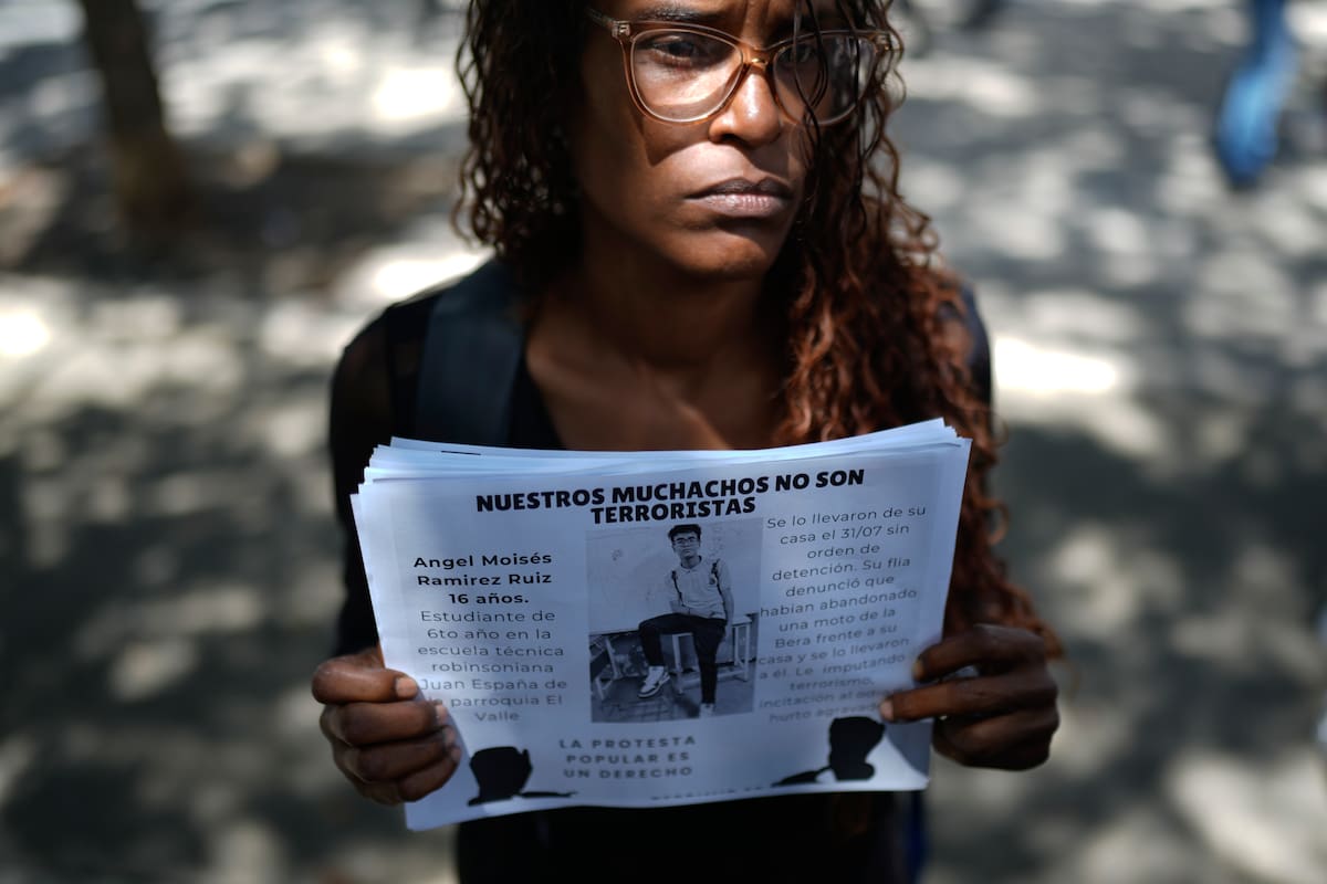 Marelys Ruiz muestra la imagen de su sobrino de 16 años detenido, Ángel Ramírez, en una protesta frente a la sede de la Fiscalía General, en Caracas. (AP/Ariana Cubillos)