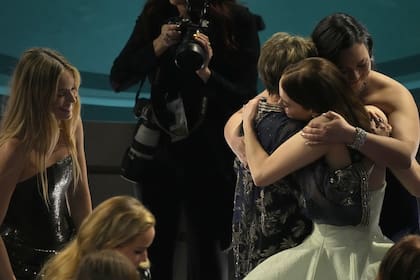 Margot Robbie, que quedó fuera de la categoría a mejor actriz principal, sonríe mientras tres de las actrices que sí lograron la nominación, Annette Bening, Lily Gladstone y Emma Stone, se abrazan cálidamente