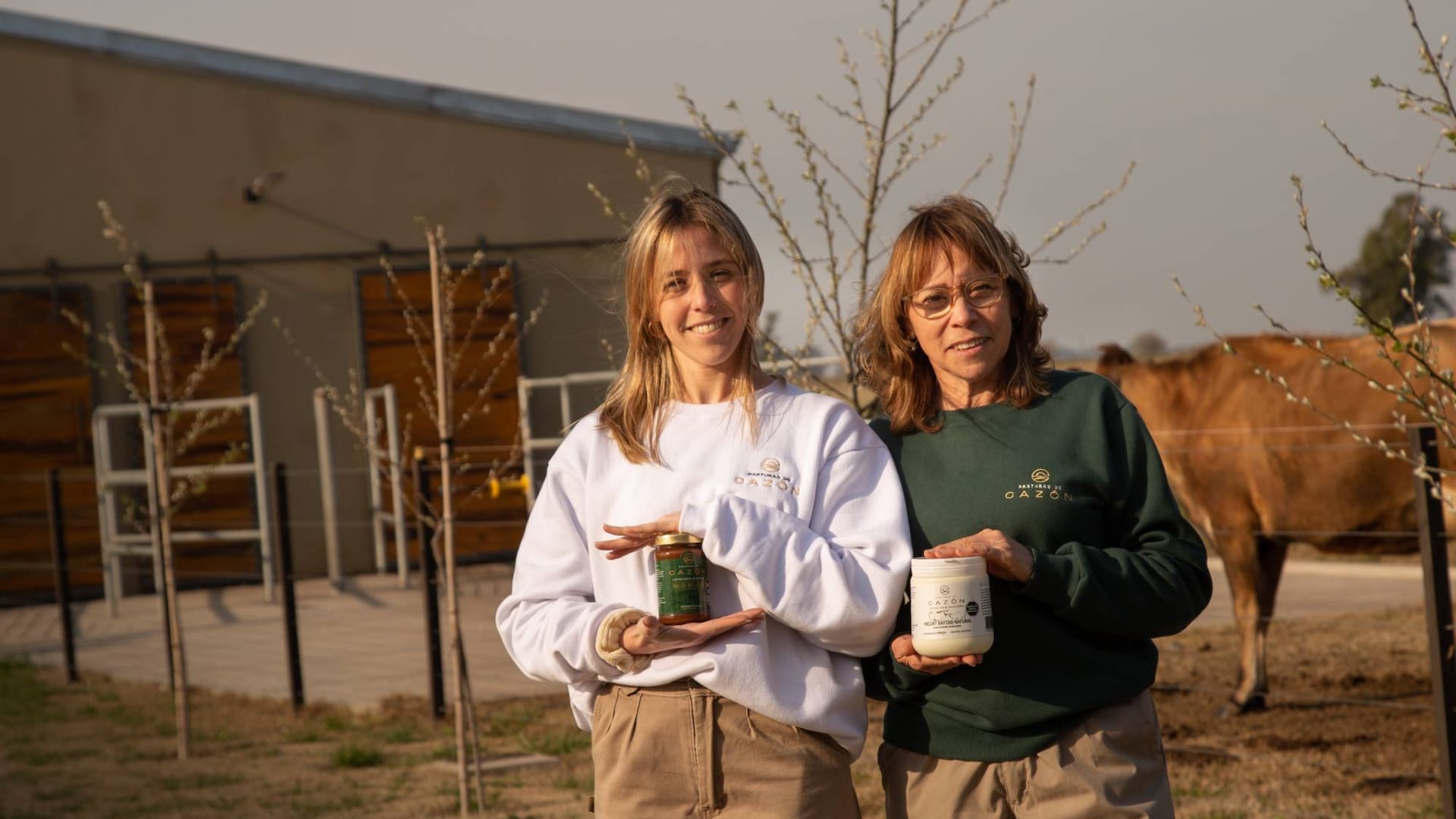 Mariel Tossi y su hija Melissa sostienen los productos de su tambo 100% natural y sin aditivos.