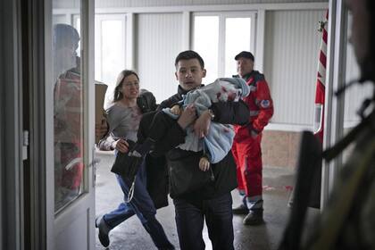 Marina Yatsko, a la izquierda, corre detrás de su novio Fedor cargando a su hijo Kirill, de 18 meses, que resultó mortalmente herido en un bombardeo, mientras llegan a un hospital en Mariupol, Ucrania, el 4 de marzo de 2022.