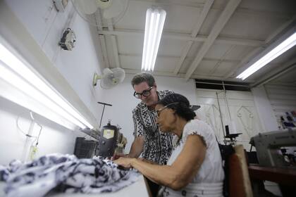 Mario Freixas, propietario de un taller de ropa de alta costura y diseñador de vestuario, junto a una de sus costureras en su taller en La Habana, Cuba, el martes 14 de mayo de 2024. "Es una prenda importante, que nos identifica. Cuando se piensa en Cuba se piensa en la guayabera, el tabaco y la palma real”, dijo Freixas. (Foto AP/Ariel Ley)