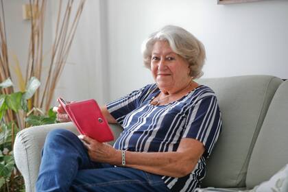 Martha Chiesa vive en colegiales, tiene 86 años y durante toda la pandemia casi no salió de su casa. En su living lee un libro en una tablet.