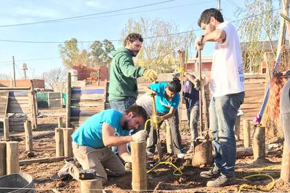 Martín (agachado en el piso) junto a a otros voluntarios construyendo lo cimientos de una futura casa