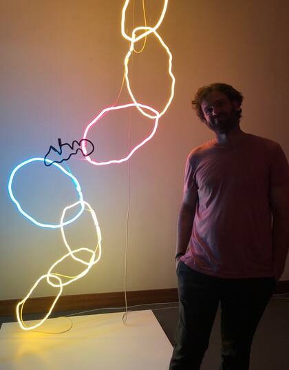 Martín Touzón con su obra, ubicada en el ingreso a la nueva sede de la feria