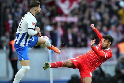 Marvin Plattenhardt, del Hertha Berlín, intenta hacer contacto con el balón rente a Noussair Mazraoui, del Bayern Múnich (AP Foto/Michael Sohn)
