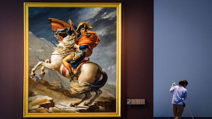 Una empleada de limpieza junto a la pintura titulada "Napoleón Bonaparte, primer cónsul, cruzando los Alpes" del artista francés Jacques-Louis David