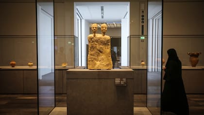 Una mujer junto a la "Estatua monumental con dos cabezas" de Jordania hacia el año 6500 a.C.