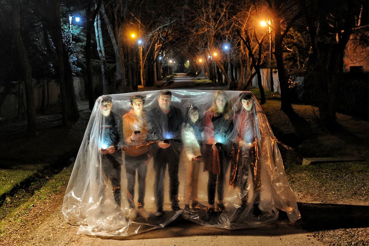 Material de ARGRA: única publicación para la difusión de la "Muestra de Fotoperiodismo Argentino Edición 32º – Periodo 2020" ARGRA
Lugar de la toma: VILLA ELISA, BUENOS AIRES
Fecha de la toma: JULIO 2020
Epigrafe: La familia de la burbuja. Retrato de una familia en su BURBUJA como metáfora de espacio seguro y libre de gérmenes, iluminados por sus celulares, medio de comunicación con el cual se conectaban al mundo en tiempos de la "nueva anormalidad” Foto Martín Bonetto. Julio 2020. Villa Elisa, BS AS.