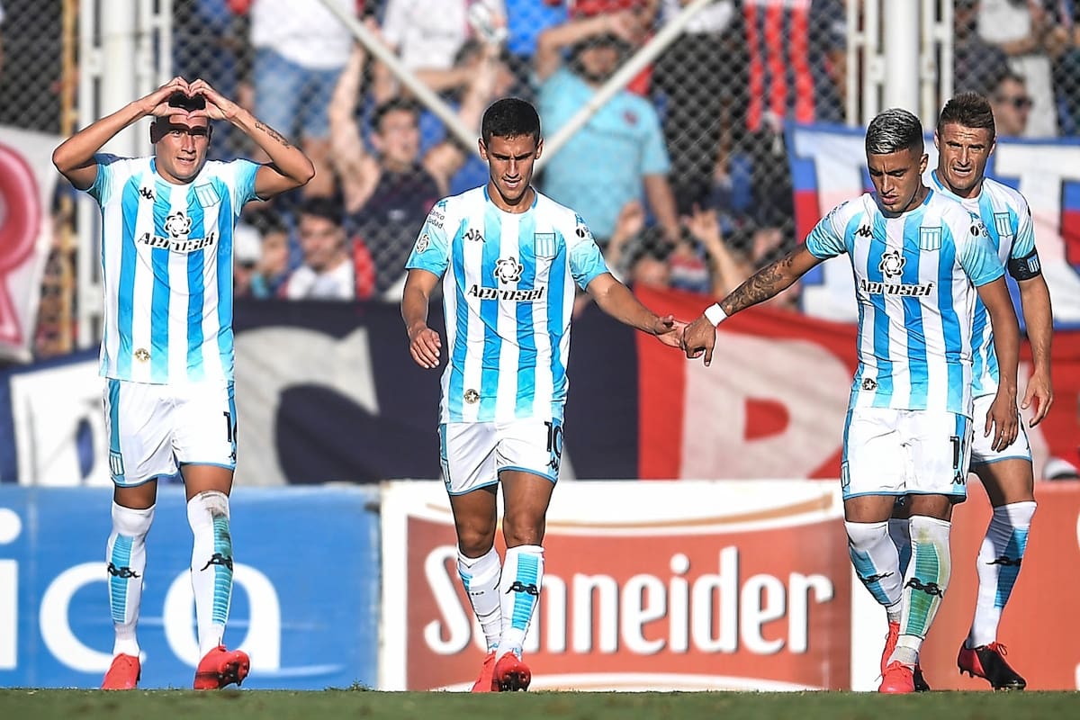 Matías Rojas (en el centro) recibe el saludo de Lolo Miranda; el zurdo desequilibra por el centro del juego de Racing