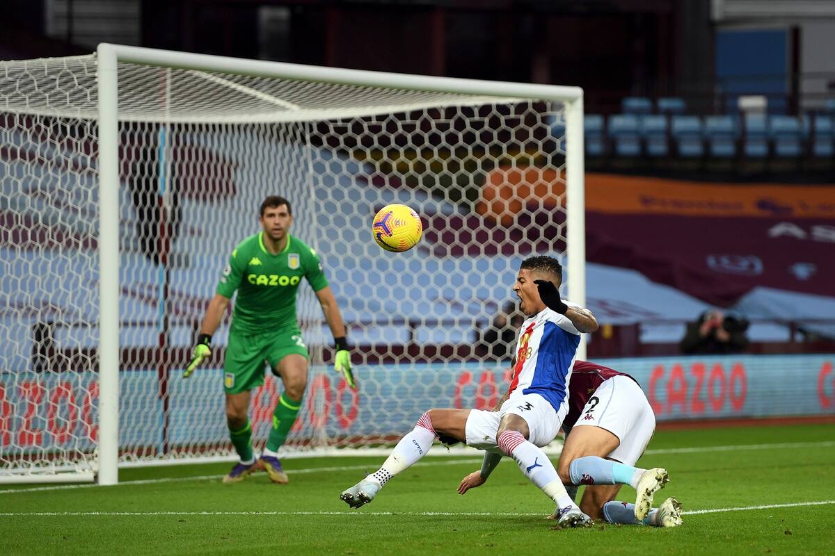 Matty Cash (der), del Aston Villa, y Patrick van Aanholt del Crystal Palace, disputan la pelota ante la atenta mirada de Emiliano Martínez.