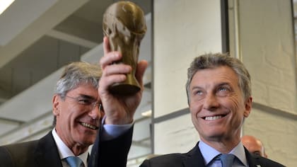 Mauricio Macri alza una imitación del trofeo de la copa del mundo que le obsequió el CEO de Siemens, Joe Kaeser (izq)