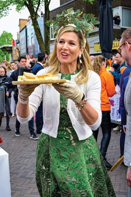 Máxima, pura sonrisa, reparte los célebres tompouces (pasteles de cumpleaños) entre la gente.