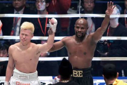 Mayweather levanta la mano de Nasukawa, su oponente, después del nocaut.