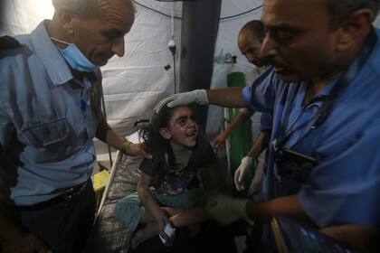 Médicos atienden a una niña herida en el hospital de Najar tras un ataque aéreo israelí sobre el edificio donde vivía su familia en Rafah, en el sur de la Franja de Gaza, el sábado 6 de agosto de 2022. (AP Foto/Hatem Ali)