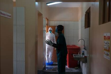 Médicos desinfectándose después de visitar a un enfermo que estuvo en contacto con una víctima de ébola, el jueves 20 de octubre de 2022, en una sección aislada del Hospital Regional en Entebbe, Uganda. (AP Foto/Hajarah Nalwadda)