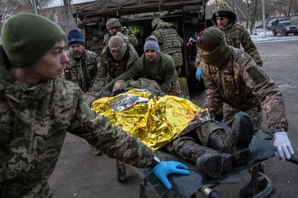 Médicos militares ucranianos trasladan a un soldado ucraniano herido desde el campo de batalla a un hospital en la región de Donetsk, en Ucrania, el lunes 9 de enero de 2023. El soldado no sobrevivió. (AP Foto/Evgeniy Maloletka)