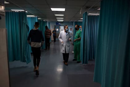 Médicos y médicos palestinos caminan dentro de la sala de emergencias del hospital Shifa en la ciudad de Gaza, el jueves 13 de mayo de 2021. Hace apenas unas semanas, el débil sistema de atención médica de la Franja de Gaza estaba luchando con un aumento desbocado de casos de coronavirus. Ahora, los médicos de todo el abarrotado enclave costero están tratando de mantenerse al día con una crisis muy diferente: heridas por explosiones y metralla, cortes y amputaciones.