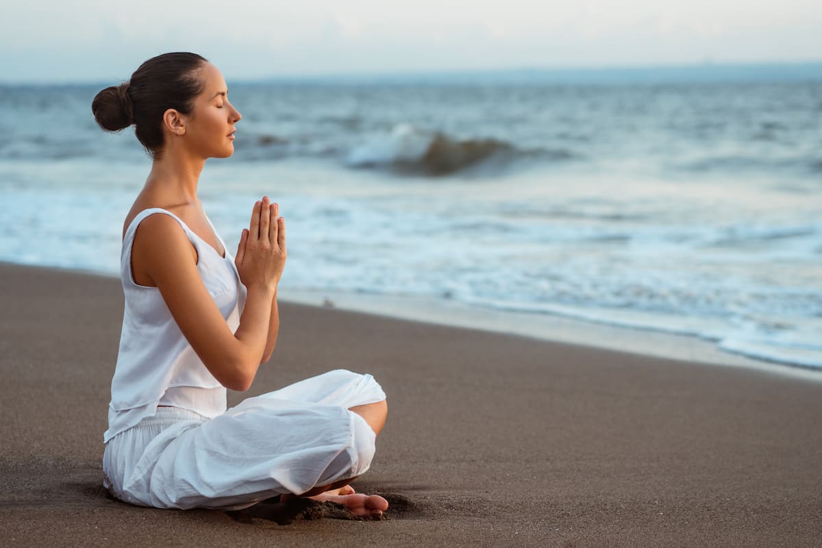 Meditating woman on the beach