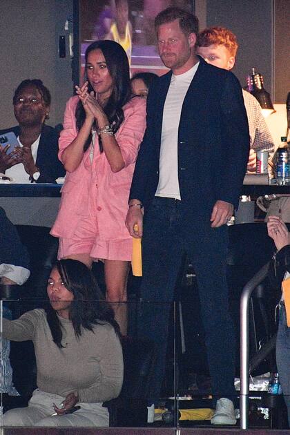 Meghan eligió un conjunto de pantalón corto y chaqueta en color rosa de la marca Staud, que combinó con stilettos Aquazzura y cartera Prada. A su lado, Harry con jeans, remera, blazer y zapatillas blancas.