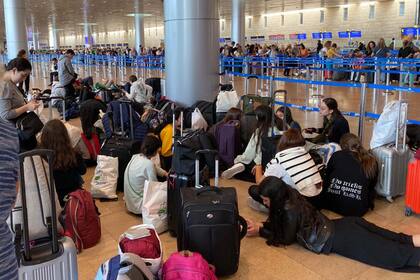 Menores argentinos sentados en el suelo de la terminal 3 del aeropuerto Ben Gurión, en Tel Aviv, a la espera de tomar un puente aéreo de repatriación