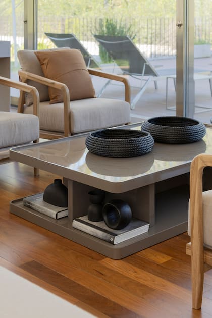 Mesa baja (Margen por Fallone) de madera laqueada en un color tintométrico (Sherwin-Williams) con acabado brillante. Sillones individuales (Margen por Fallone) con estructura de madera, tientos de cuero y almohadones (LB Géneros). Objetos de cerámica (A.Hus), canastos negros (Andy Forn Casa).