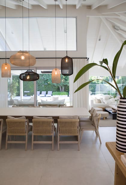 Mesa con base de madera y tapa de Caesarstone y sillas con respaldo de cordón de papel (Estudio Mariana Flombaum). Lámparas colgantes ‘Kute’ (Atmosphère d’Ailleurs)