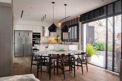 Mesa con patas de madera maciza y tapa de Dekton ‘Calacatta Gold’. (MTD Arquitectura), sillas (Navarro Hábitat), lámparas colgantes (E27 Iluminación).