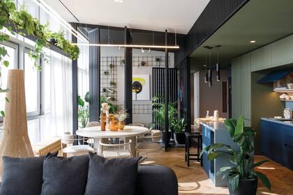 Mesa con sillas de distintos modelos (todo de Bull Buenos Aires), pero el mismo tono de tapizado (Tienda Mayor). Sobre el estante entre columnas, plantas (Mercedes Plazibat) en macetas de cerámica (Estudio Pelli).