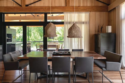 Mesa con tapa de madera maciza y patas metálicas esmaltadas y sillas ‘Baru’ con y sin apoyabrazos (todo de Solsken), estas últimas distinguidas en 2020 con el Sello de Buen Diseño Argentino. En el extremo de la galería asoma la parrilla.